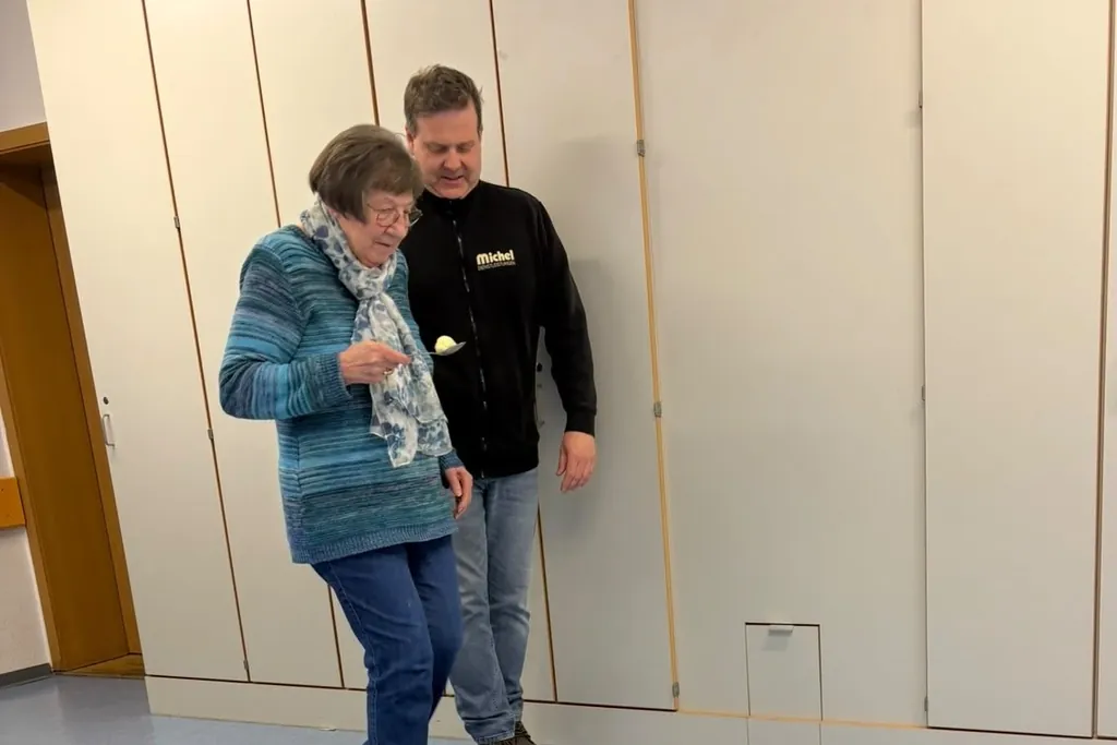 Ein Mitarbeiter von Michel Dienstleistungen begleitet eine Seniorin beim Eierlauf