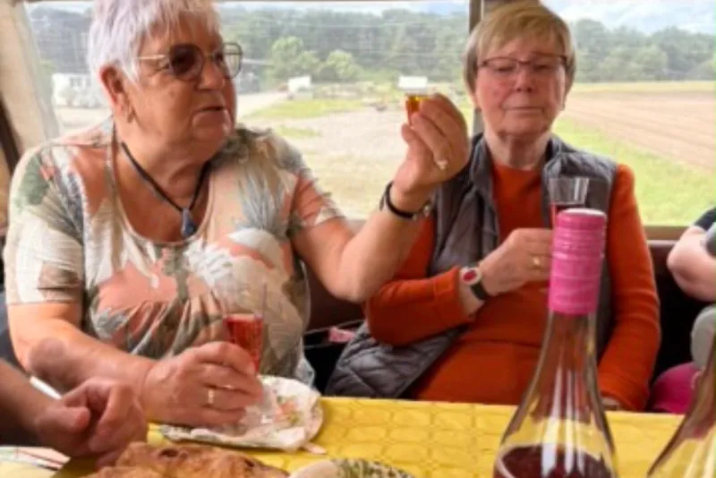 Zwei Gäste des Tagwerk West stoßen am gedeckten Tisch mit Kuchen an